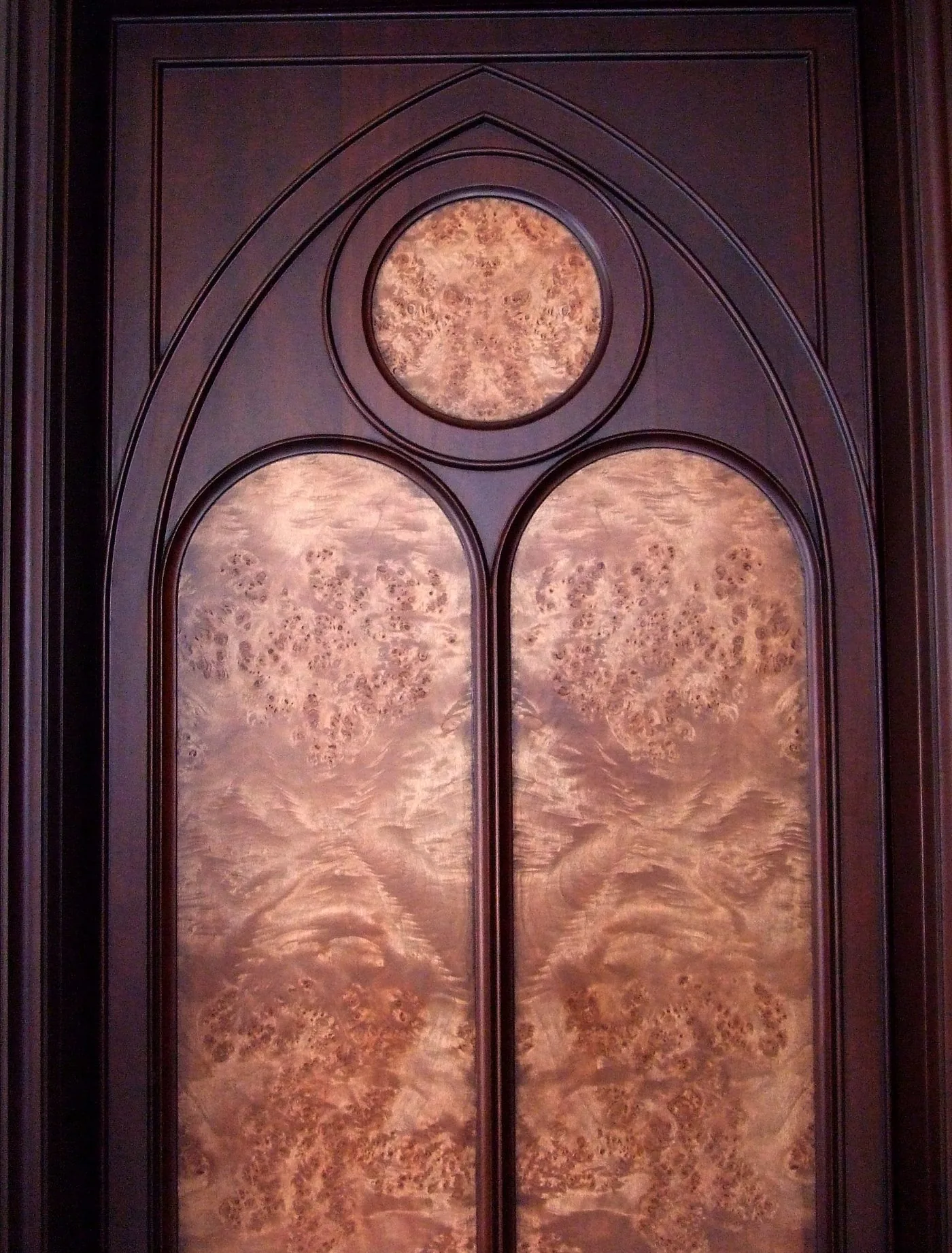 Arched door with book-matched burl panels by Elite Woodwork